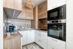 Una cocina moderna con armarios de madera, microondas empotrado y horno.
