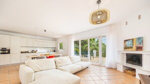 Un salon moderne comprenant un canapé, une cheminée et un coin cuisine avec des placards et une table à manger.