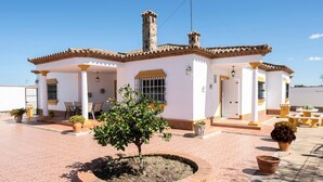A two-story building with a tiled roof, a central chimney, and a small garden area with potted plants. - Holiday Home 'Villa Carmen' with Private Pool, Private Terrace and Wi-Fi (Conil)