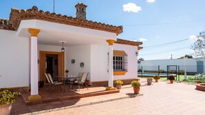 A building with a tiled roof, a covered patio with a table and chairs, and potted plants. - Holiday Home 'Villa Carmen' with Private Pool, Private Terrace and Wi-Fi (Conil)