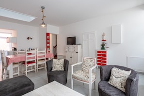 A modern living room with a dining area, white walls, and a red and white checkered tablecloth. - Family Holiday Home with Private Terrace and Wi-Fi (Les Sables-d'Olonne)