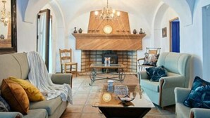 Un salon avec une cheminée, deux canapés, une table basse et un lustre.
