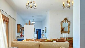 Un salon avec un canapé beige, un lustre et un miroir au mur.