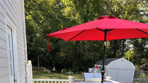 A deck with two lounge chairs and a red umbrella, a grill, and a white fence. - Peaceful Onset Beach Home. 5 Bedrooms, Wareham MA (Wareham)