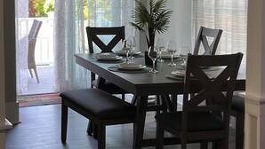 A dining area with a table set for four, chairs, a bench, and a potted plant. - Peaceful Onset Beach Home. 5 Bedrooms, Wareham MA (Wareham)