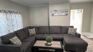 A living room with a sectional sofa, a coffee table, and a red and grey rug. - Peaceful Onset Beach Home. 5 Bedrooms, Wareham MA (Wareham)