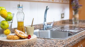 Un comptoir de cuisine avec un évier, un verre de bière, une bouteille et quelques aliments.