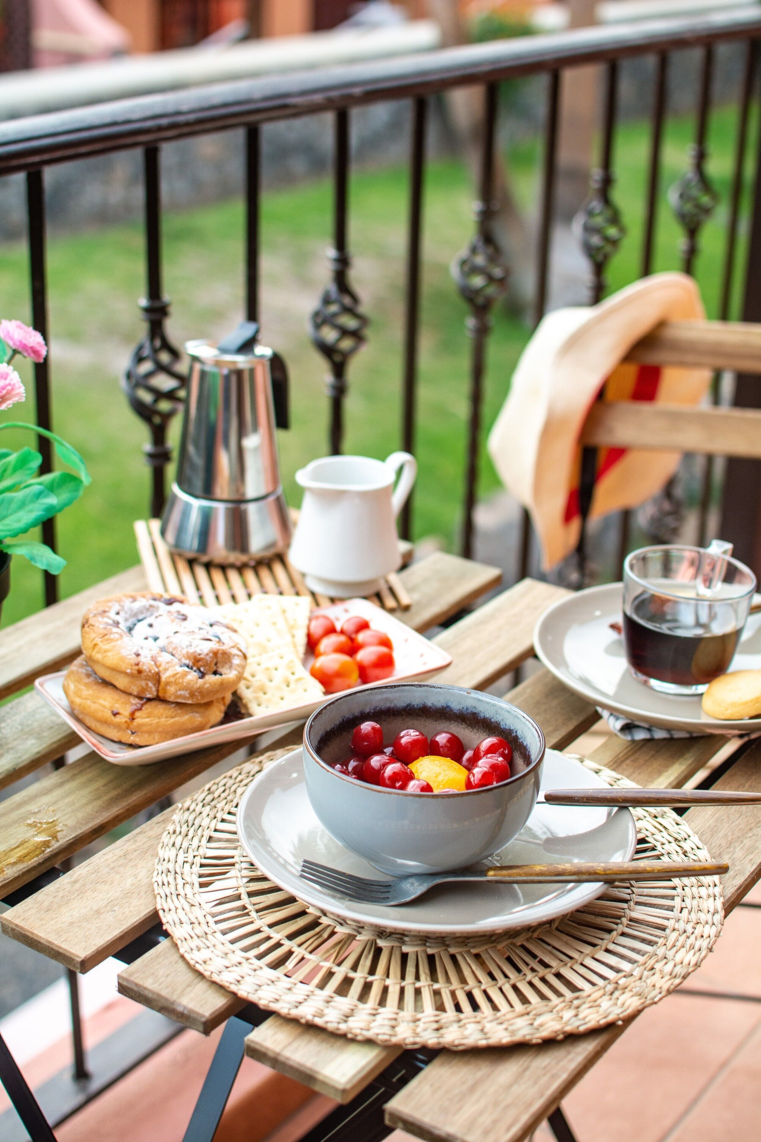 Een houten tafel met ontbijtartikelen, zoals gebak, een fruitschaal, een koffiekop en een theepot.