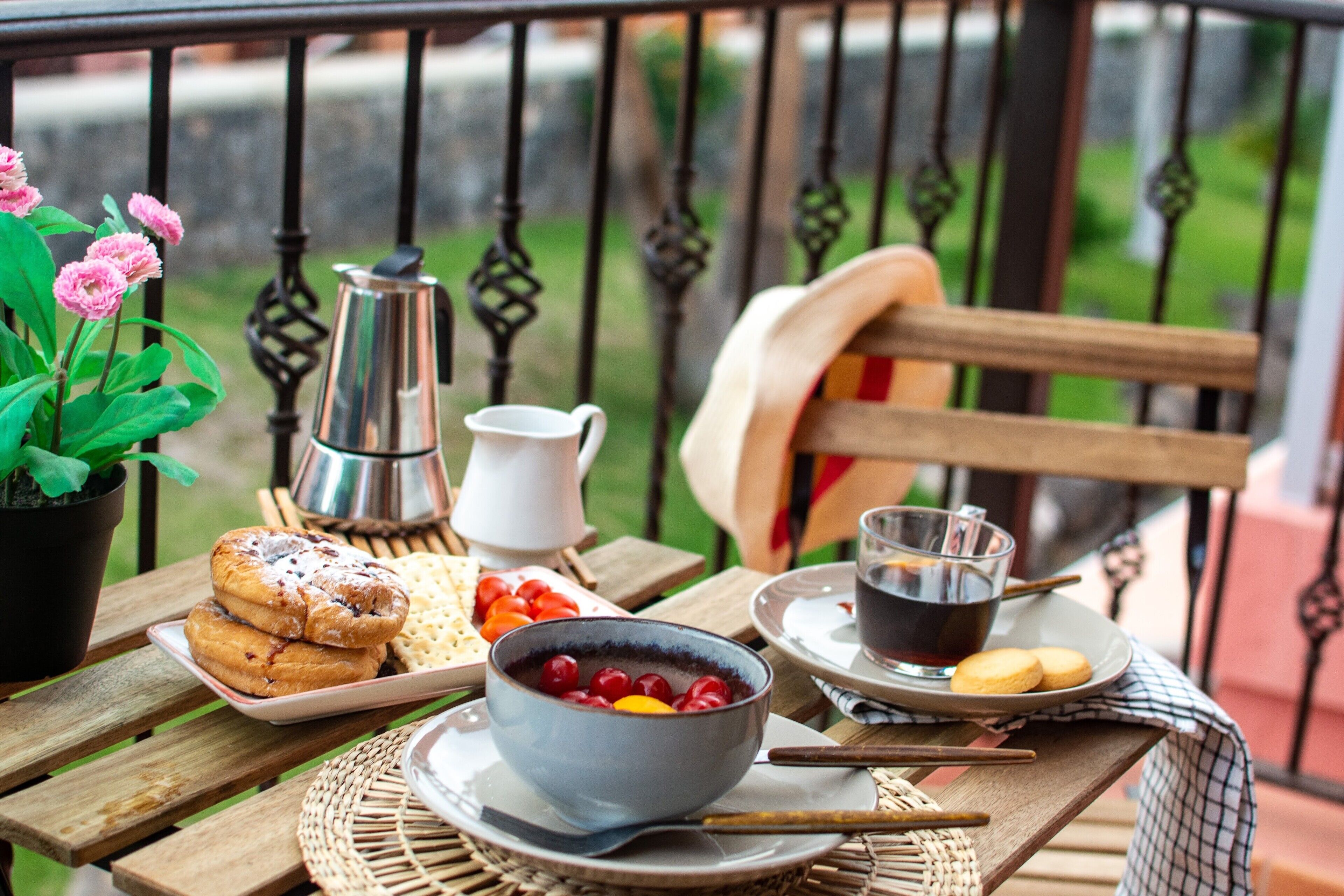 Een houten tafel met ontbijtartikelen, een fruitschaal, een koffiepot en een stoel.