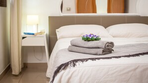 Un lit bien fait, agrémenté d’un coussin décoratif, une table de chevet avec une lampe et un miroir au-dessus du lit.