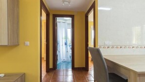Un pasillo con comedor, un armario de madera y suelo de baldosas.