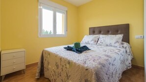 Un dormitorio con una cama, una mesita de noche, una ventana y una puerta.