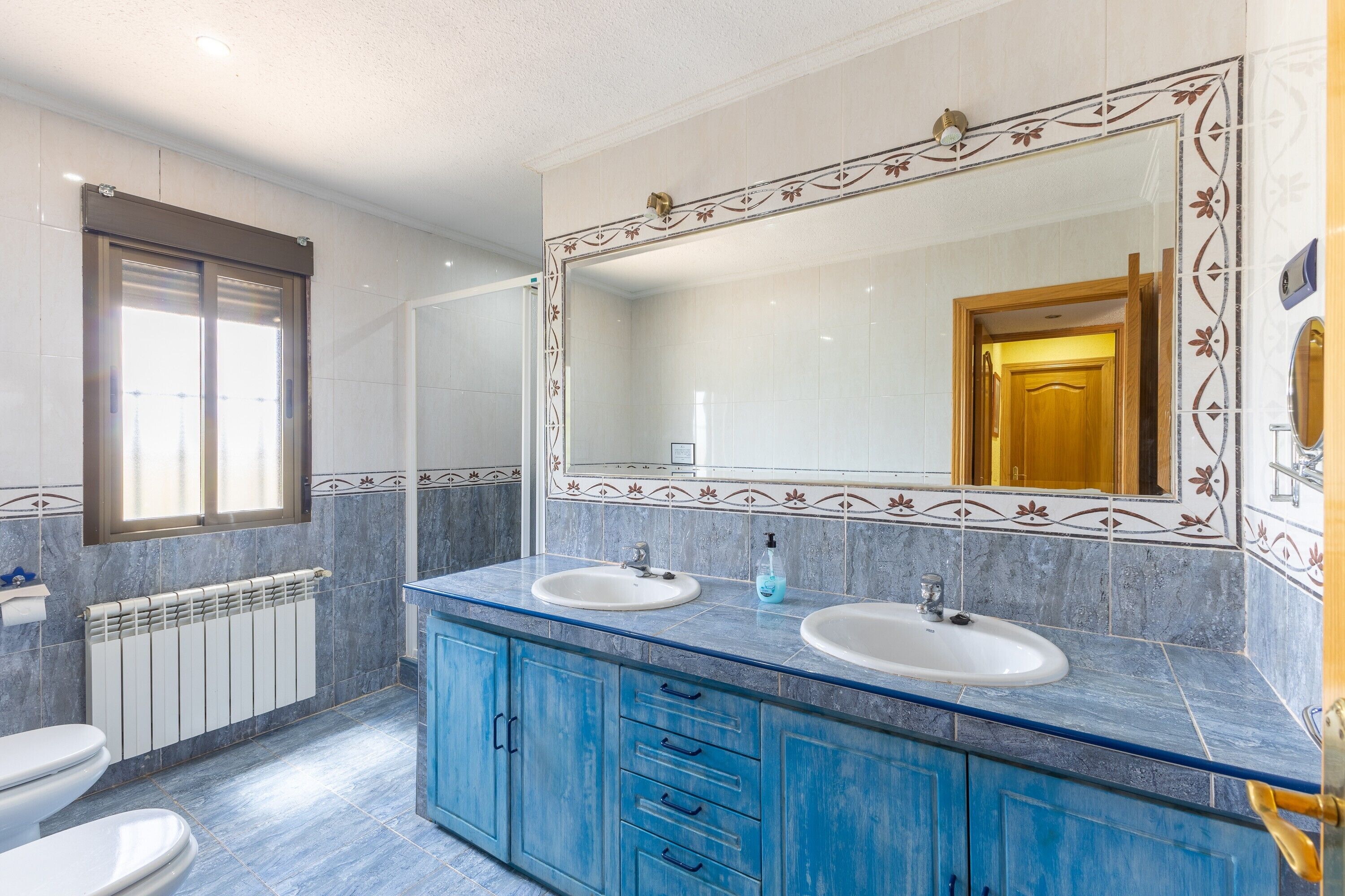 Un baño con dos lavamanos, un espejo grande y una ventana.