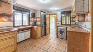 Una cocina compacta equipada con refrigerador, lavadora y cafetera.