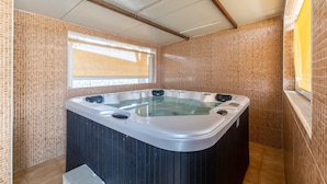 Un jacuzzi en una habitación con paredes de azulejos y una ventana.