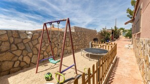 Un espace de jeux pour enfants avec des balançoires, un trampoline et un bac à sable.