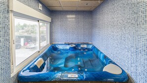 Une salle de spa équipée d’un jacuzzi, avec des murs carrelés et une fenêtre.