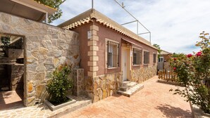 Un bâtiment en pierre avec un toit en tuiles, un petit jardin et une clôture en bois.