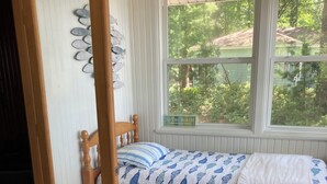 Une chambre à coucher avec un lit, une fenêtre donnant sur un paysage verdoyant et une porte en bois.