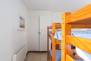 A bunk bed room with a white door, a radiator, and a framed picture on the wall.