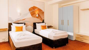 A hotel room with two beds, a large wardrobe, and a wall-mounted light fixture.