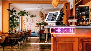 Un interior de restaurante con mostrador de recepción, suelo de madera y diferentes disposiciones de asientos.