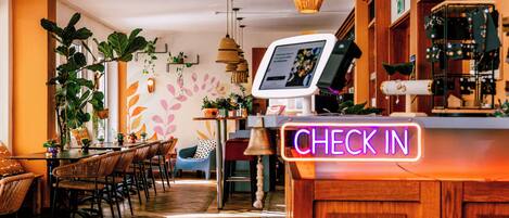 Un interior de restaurante con mostrador de recepción, suelo de madera y diferentes disposiciones de asientos.