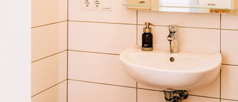 A bathroom with a white sink, a mirror, and a toilet.
