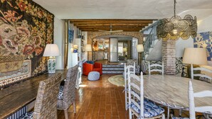 Un coin repas avec une table ronde, des chaises en osier et un mur orné d’un motif.