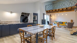 Une cuisine moderne avec des meubles de couleur sombre, un plan de travail en marbre et un coin repas avec des chaises en bois.