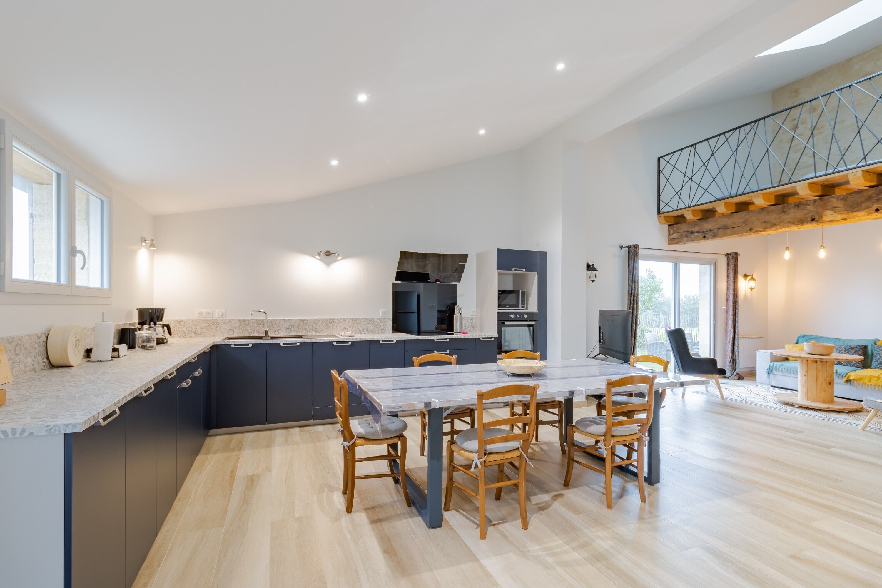 Een moderne keuken met een eetgedeelte, inbouwapparatuur en een slaapverdieping met balkon.