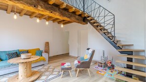 Un salon moderne avec un escalier en bois, une table ronde en bois, un canapé et un fauteuil.