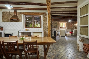 Une cuisine rustique avec un sol carrelé, des meubles en bois et un mur en pierre.