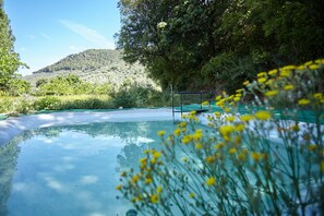 Una piscina exterior cristalina rodeada de vegetación y colinas.
