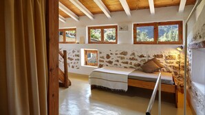 Ein rustikales Schlafzimmer mit einem hölzernen Bett, einem kleinen Fenster und einer Steinsäule.