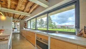 A modern kitchen with wooden cabinets, a large window, and a view of the outdoors.