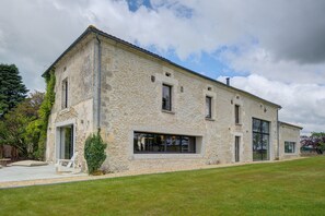 A stone building with large windows and a grassy yard.