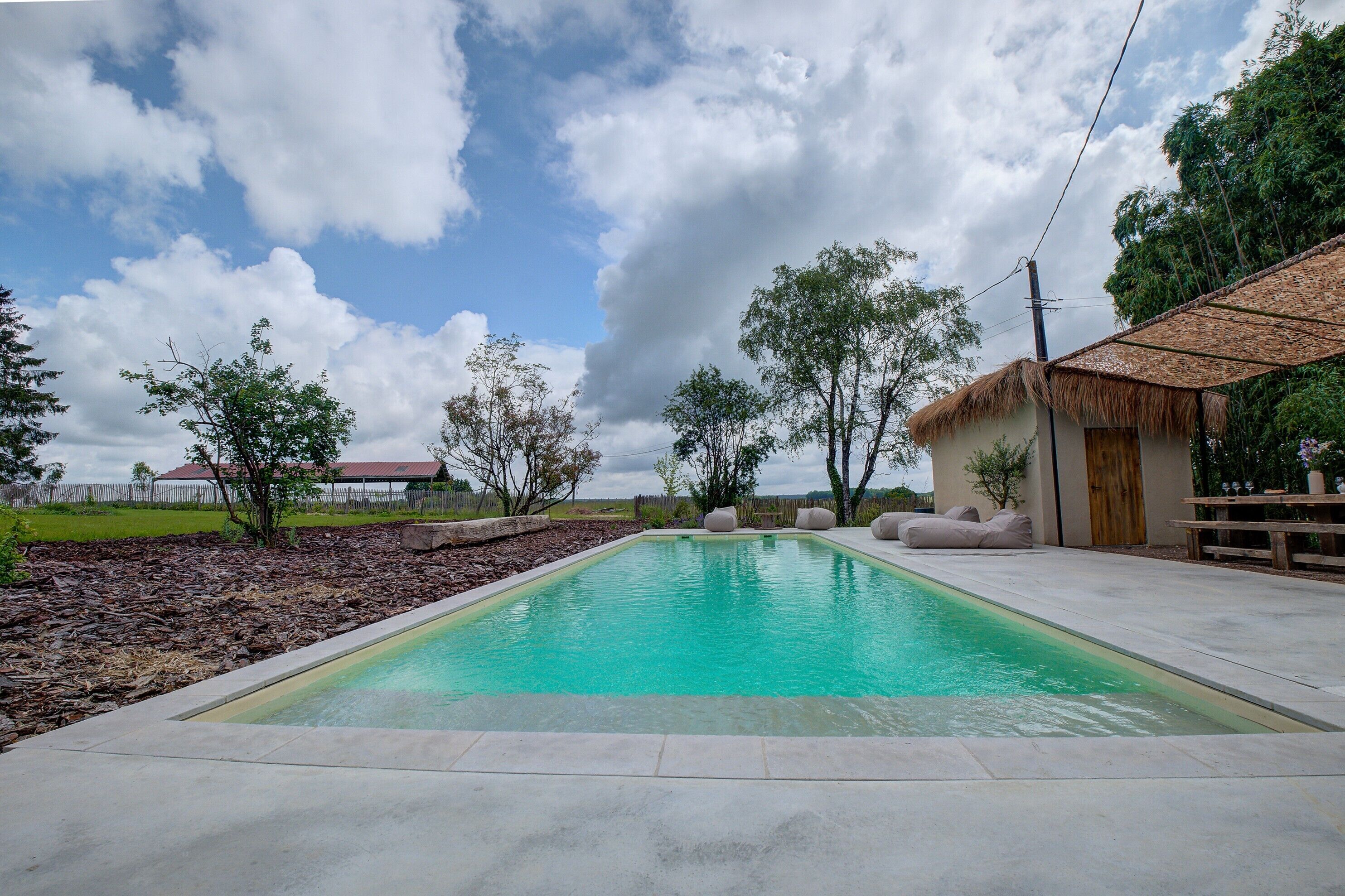 Una piscina rectangular con superficie de agua azul cristalina, rodeada por una plataforma de hormigón.