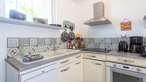 Una cocina con ventana, estufa, fregadero y cafetera.