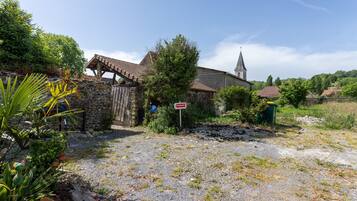 Una iglesia rural con un muro de piedra, estructura de madera y un estacionamiento de grava.
