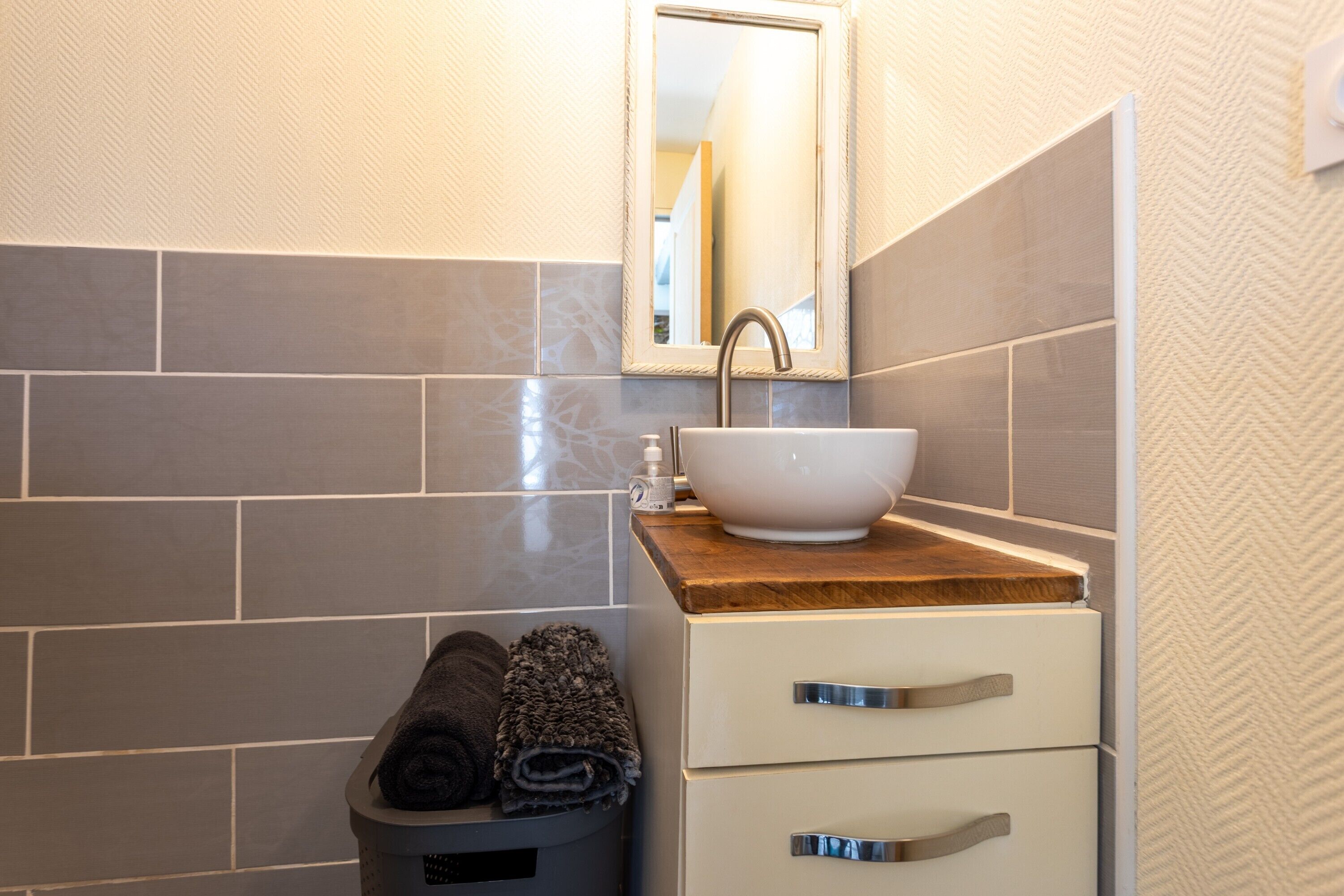 Une salle de bain équipée d’un lavabo, d’un miroir, d’un porte-serviettes et de tiroirs.