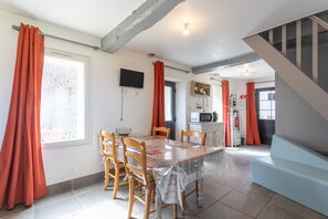 Un comedor con mesa, sillas y televisor montado en la pared.