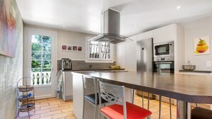 Een moderne keuken met een centraal eiland, roestvrijstalen apparatuur en een groot raam.