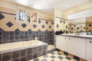 Un baño con una bañera, un lavamanos y un espejo.