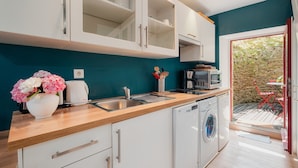 Een moderne keuken met een wasmachine, een koffiezetapparaat en een bloemenvaas.