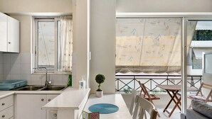 A compact kitchen with a sink, a small potted plant, and a dining area with a table and chairs. - Apartment 'Pallada' with Balcony, Wi-Fi and Air Conditioning (Athina)
