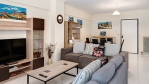 A modern living room with a flat-screen TV, a sofa, a coffee table, and a bookshelf. - Apartment 'Pallada' with Balcony, Wi-Fi and Air Conditioning (Athina)