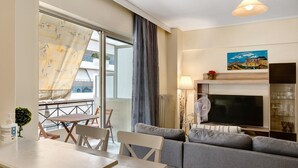 A modern living room with a sofa, a TV, and a dining area with a table and chairs. - Apartment 'Pallada' with Balcony, Wi-Fi and Air Conditioning (Athina)