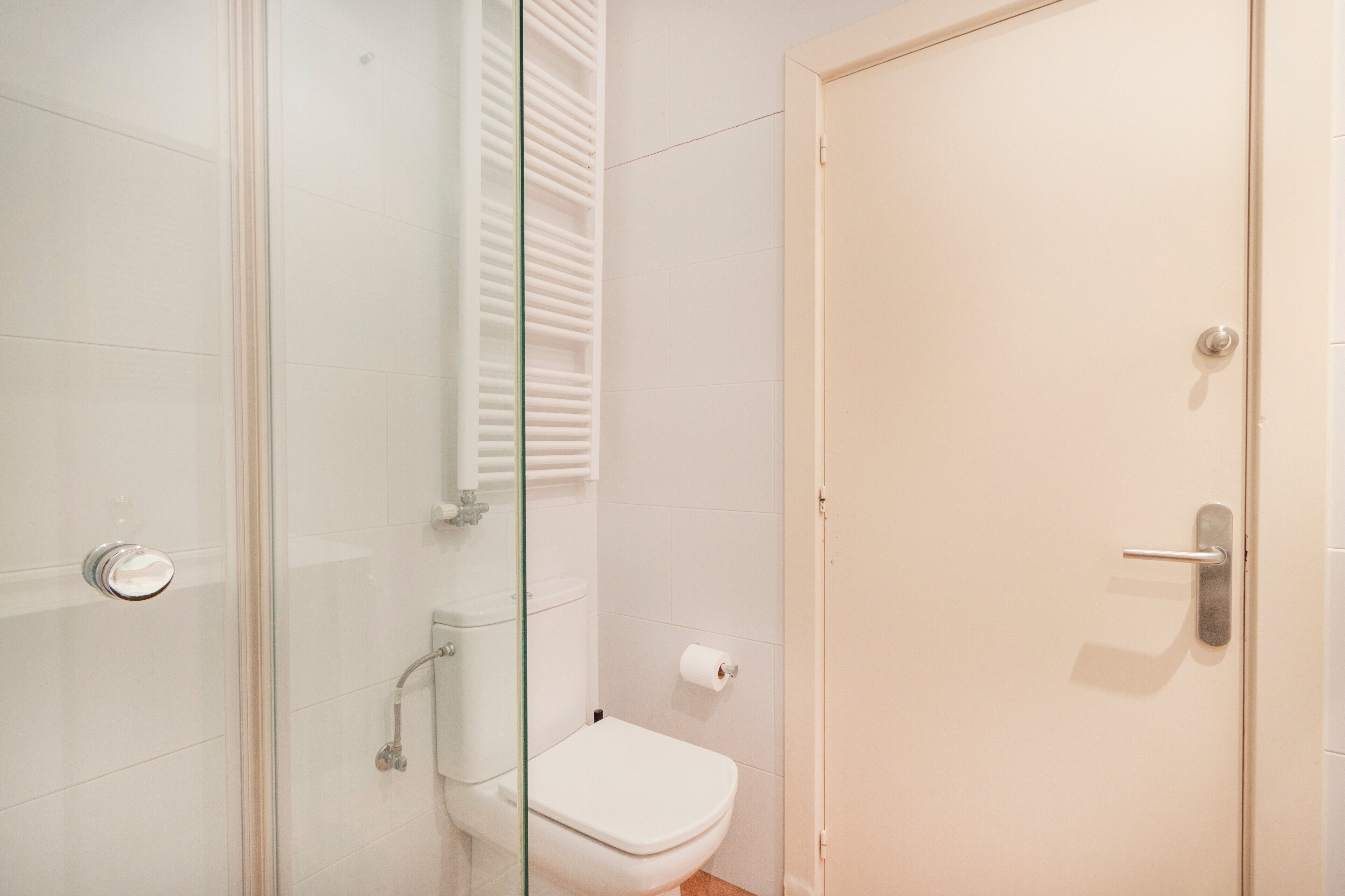 A bathroom with a glass shower enclosure, a toilet, and a door.