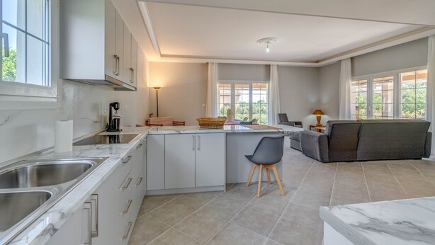 Eine moderne Küche mit Marmorarbeitsplatte, Edelstahlspüle und einer Essecke mit Sofa und Lampe.
